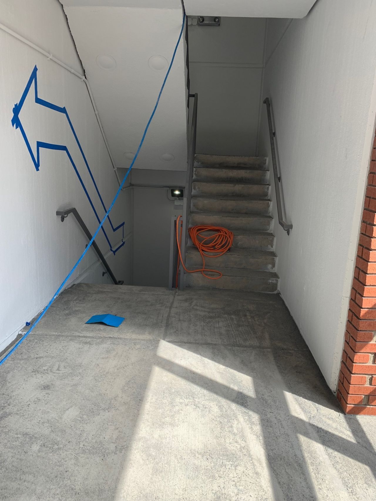 A staircase with a blue arrow painted on the wall