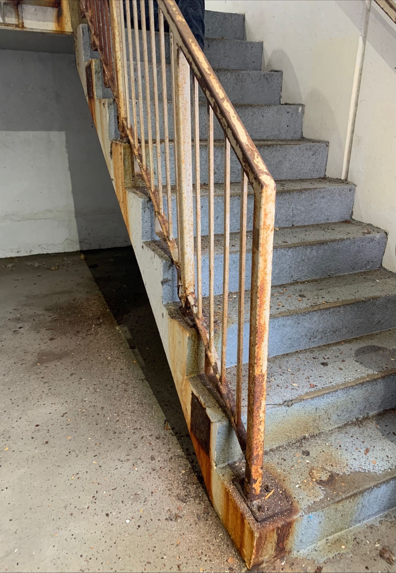 A set of stairs with a rusty railing in a building.