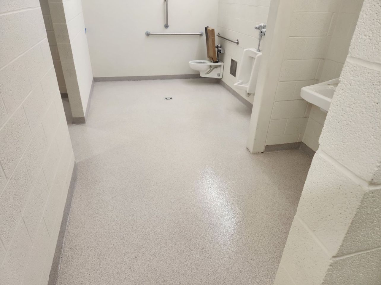 A bathroom with a toilet and urinals and a sink