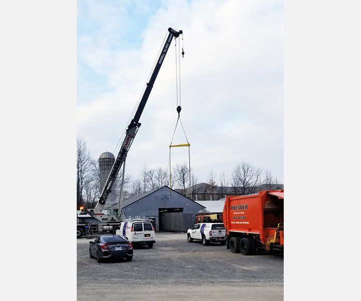 A large crane is lifting a large object in a parking lot.