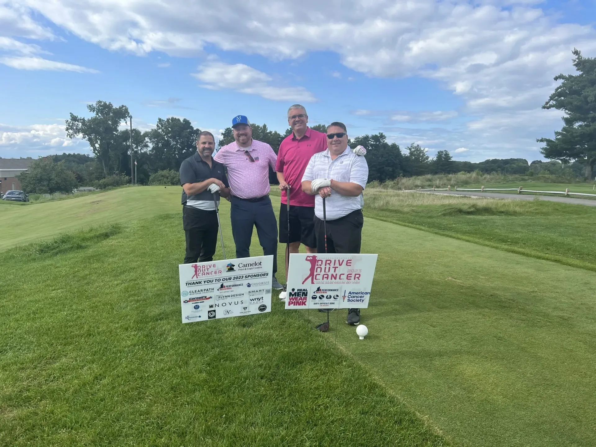 A group of men are standing on a golf course holding signs.