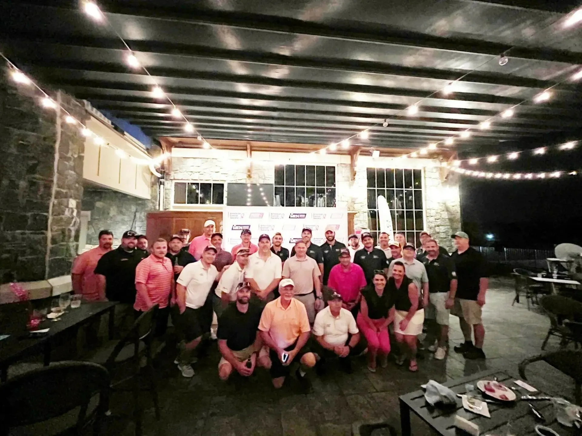 A group of people are posing for a picture on a patio at night.