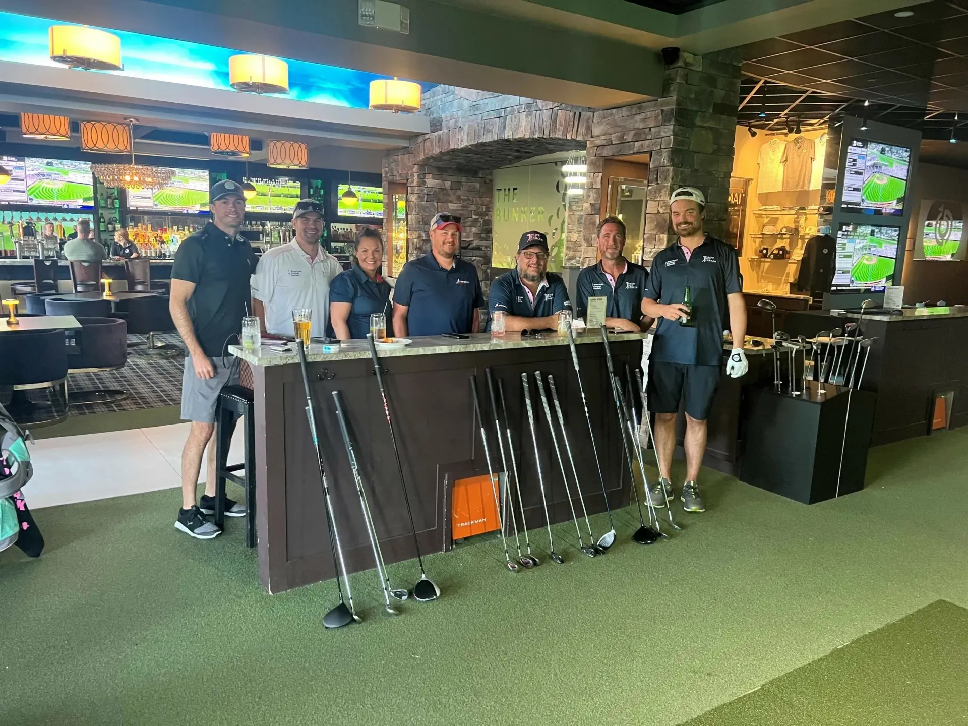 A group of men are standing in front of a bar holding golf clubs.