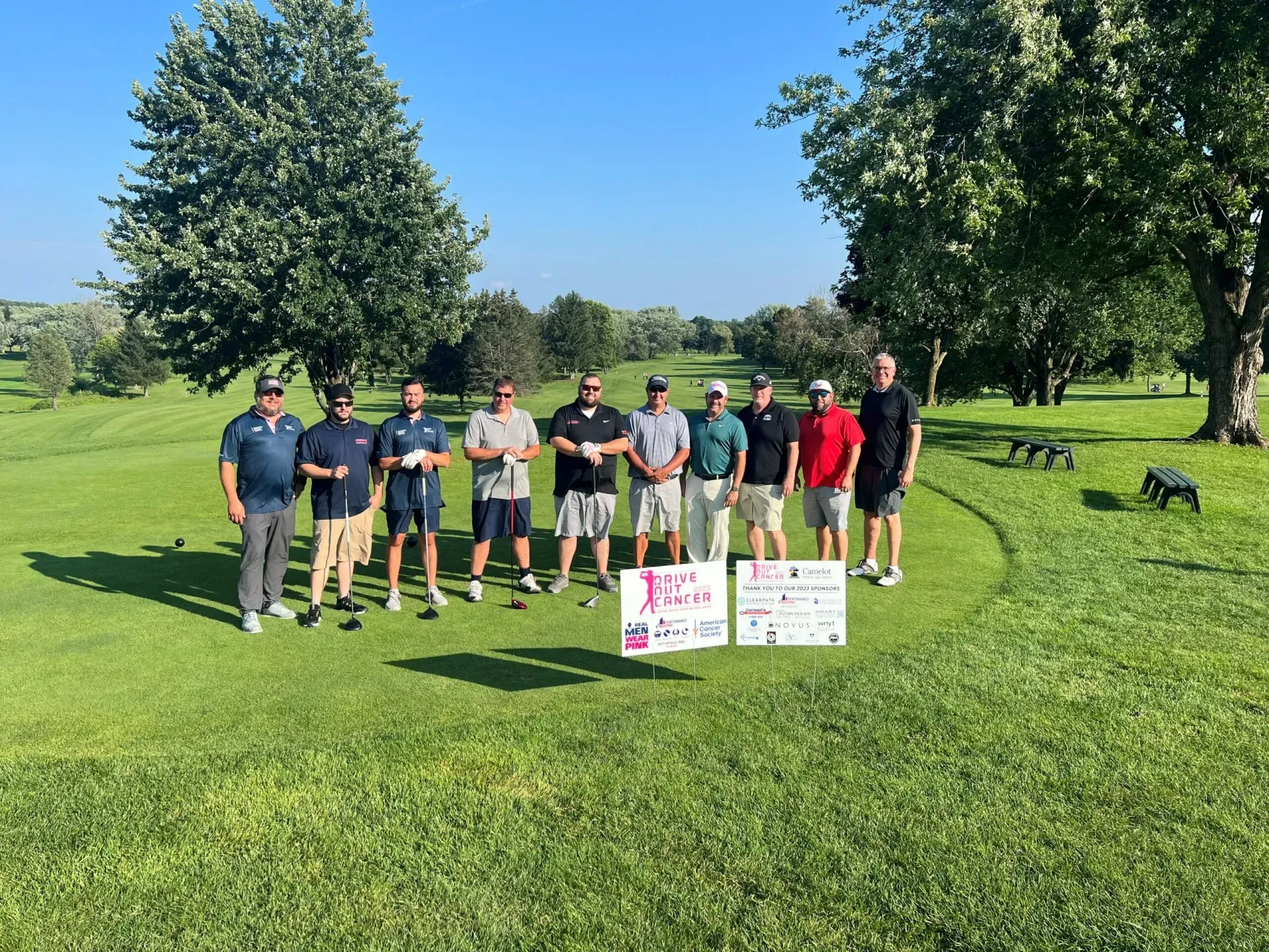 A group of men are posing for a picture on a golf course.
