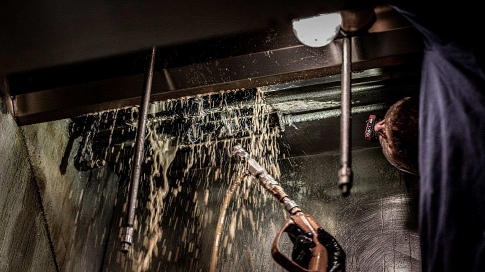 Technician using specialized tools to remove grease from restaurant exhaust hood. Technician using specialized tools to remove grease from restaurant exhaust hood.