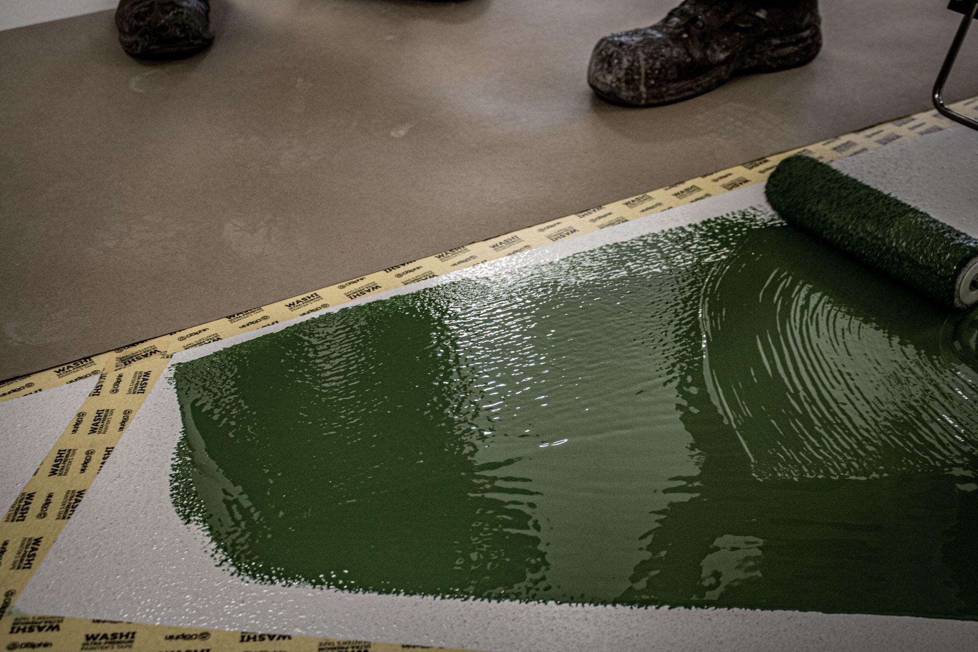 A person is painting the floor with green paint