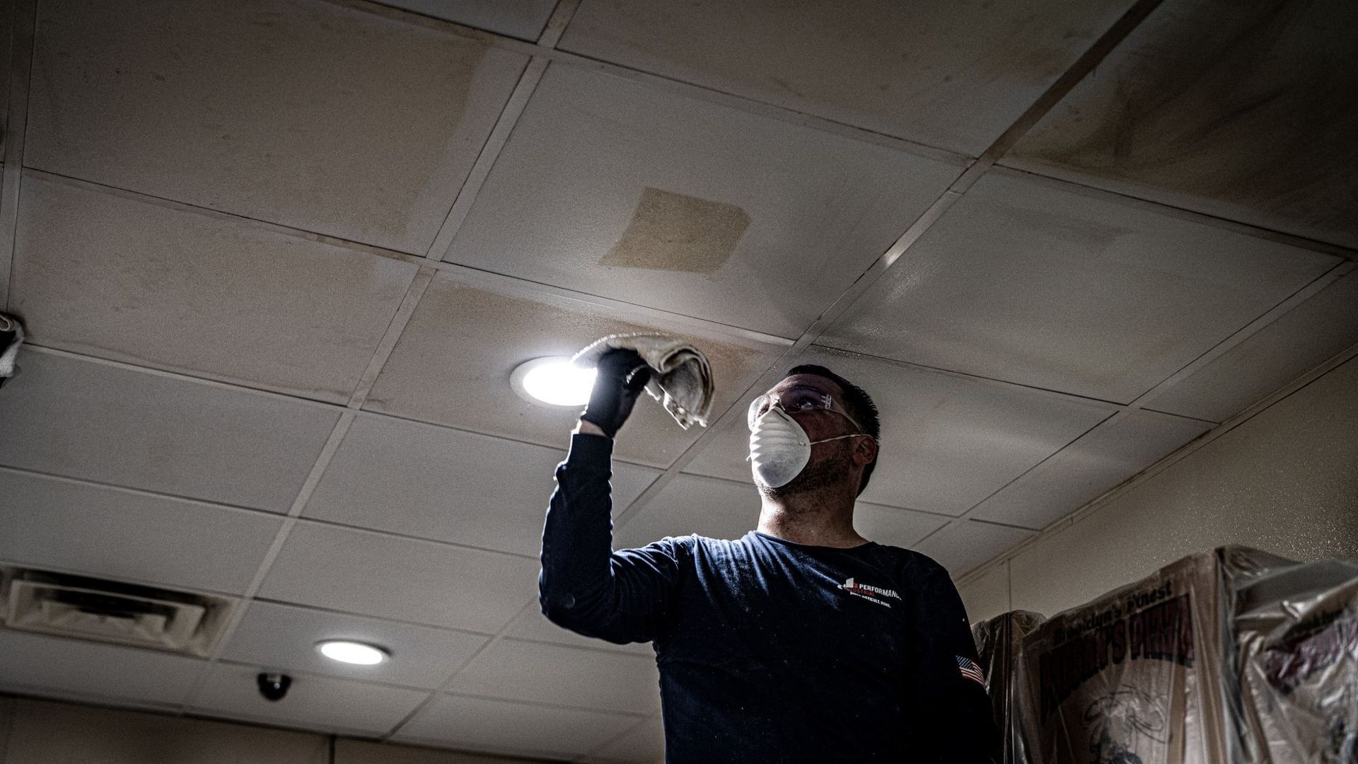 A man wearing a mask is working on a ceiling.