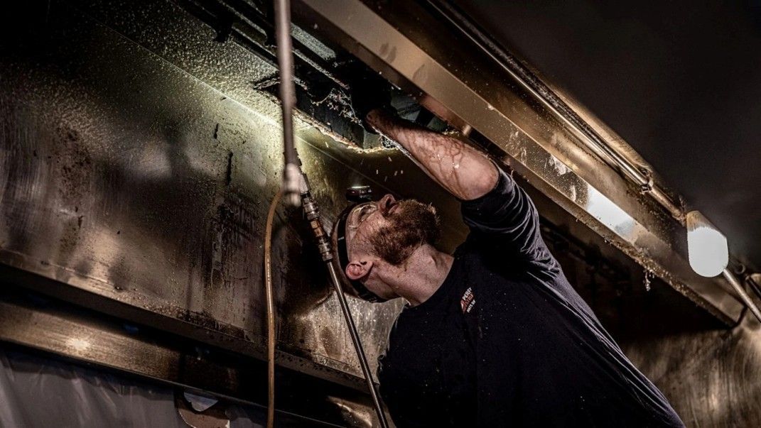 Technician performing kitchen exhaust cleaning for commercial safety and compliance. Technician performing kitchen exhaust cleaning for commercial safety and compliance.