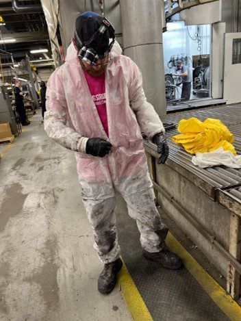 A Man In A Pink And White Coverall Is Standing In A Factory | S. Glens Falls, NY | Performance Ind.