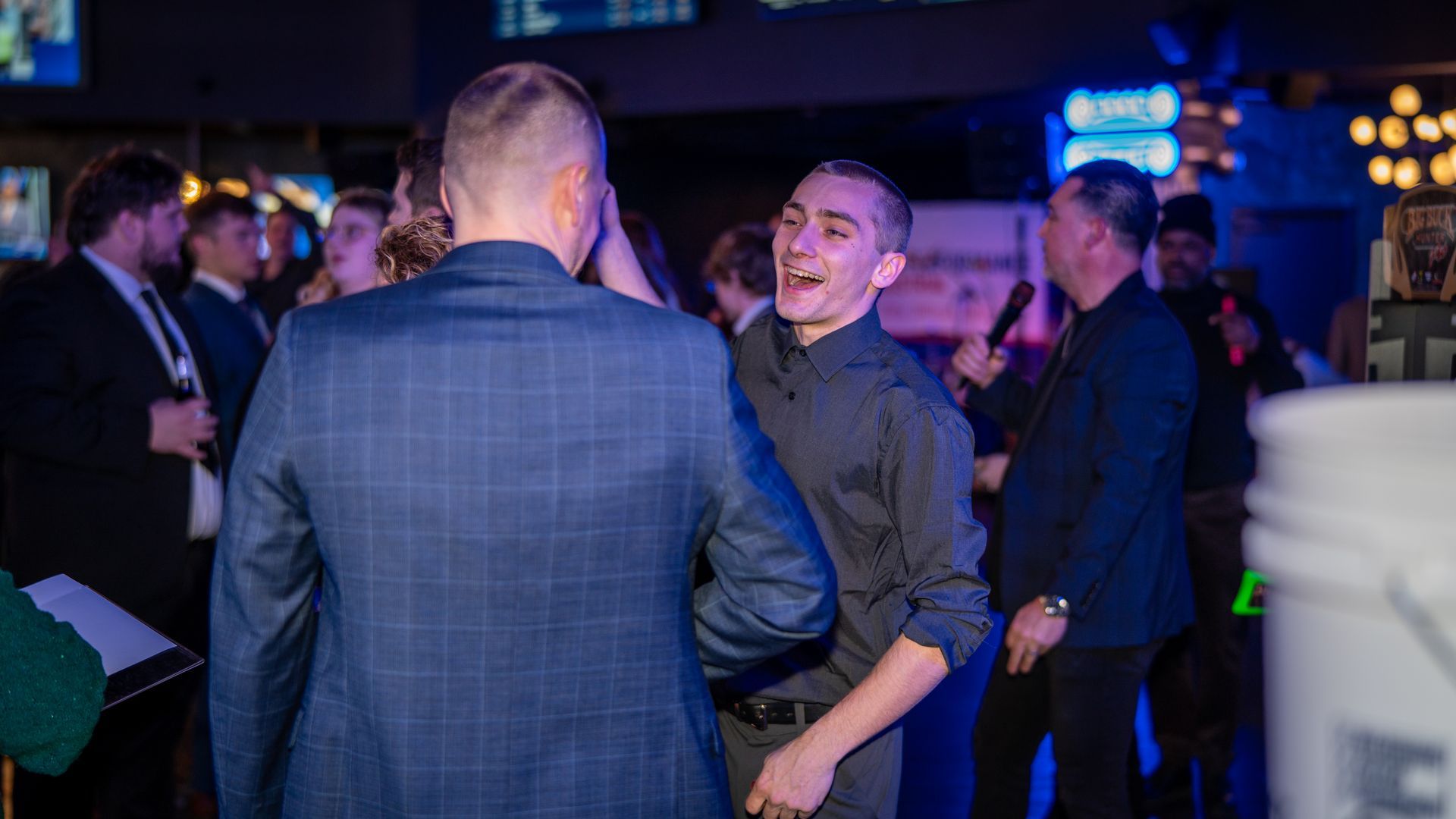 Performance Industrial employees talking and laughing together at the annual holiday appreciation party inside a private event venue with music and entertainment.
