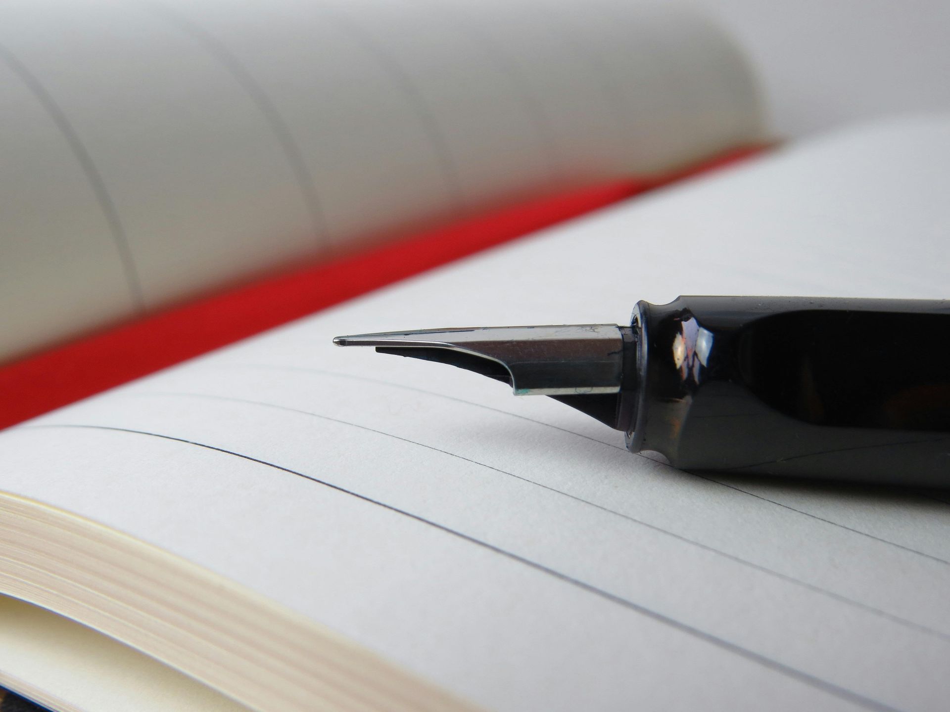 Black fountain pen resting on an open notebook with lined paper.