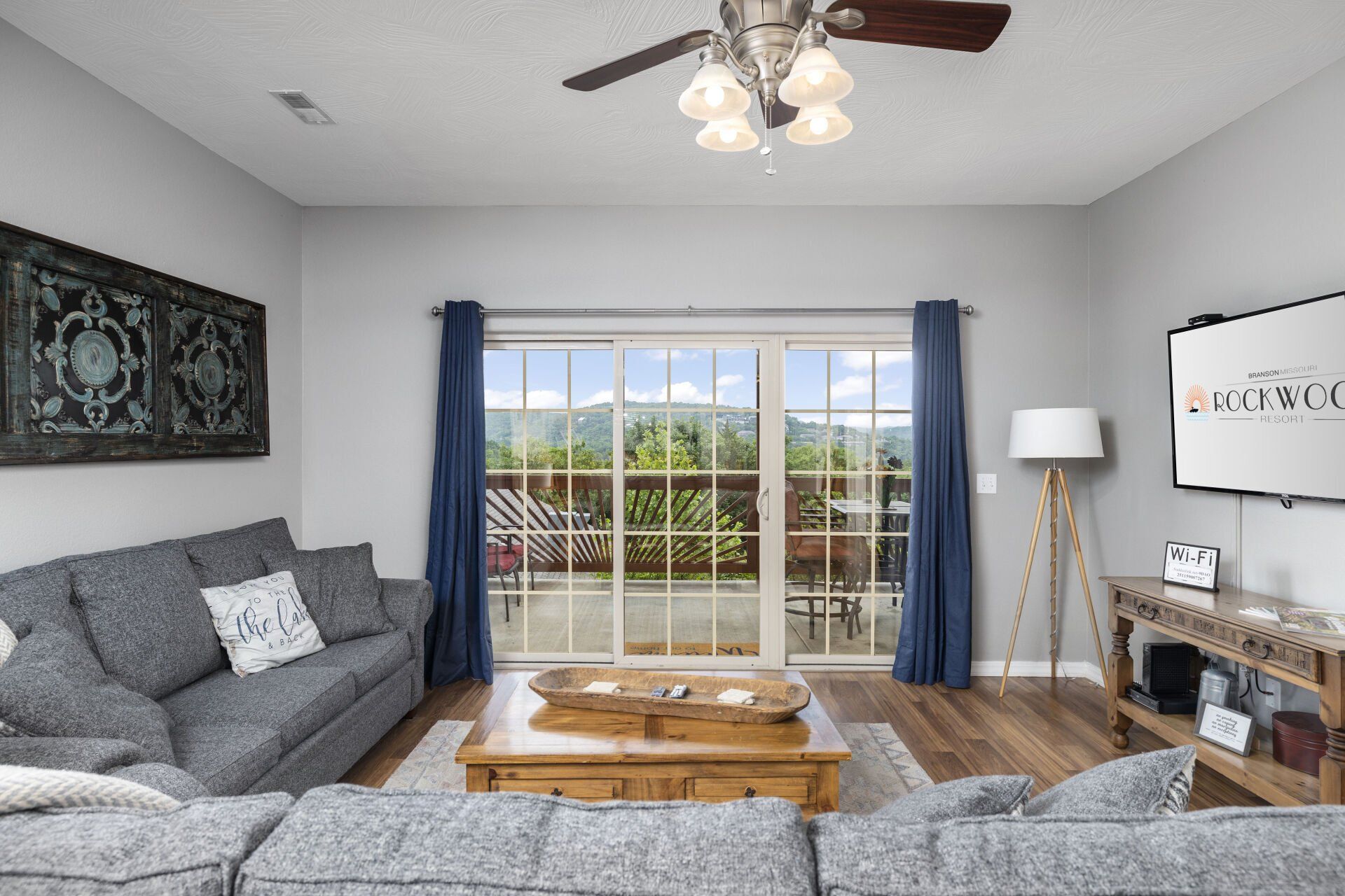 Bright living room with gray sofas, coffee table, fireplace, floor lamp, and sliding doors to a balcony.