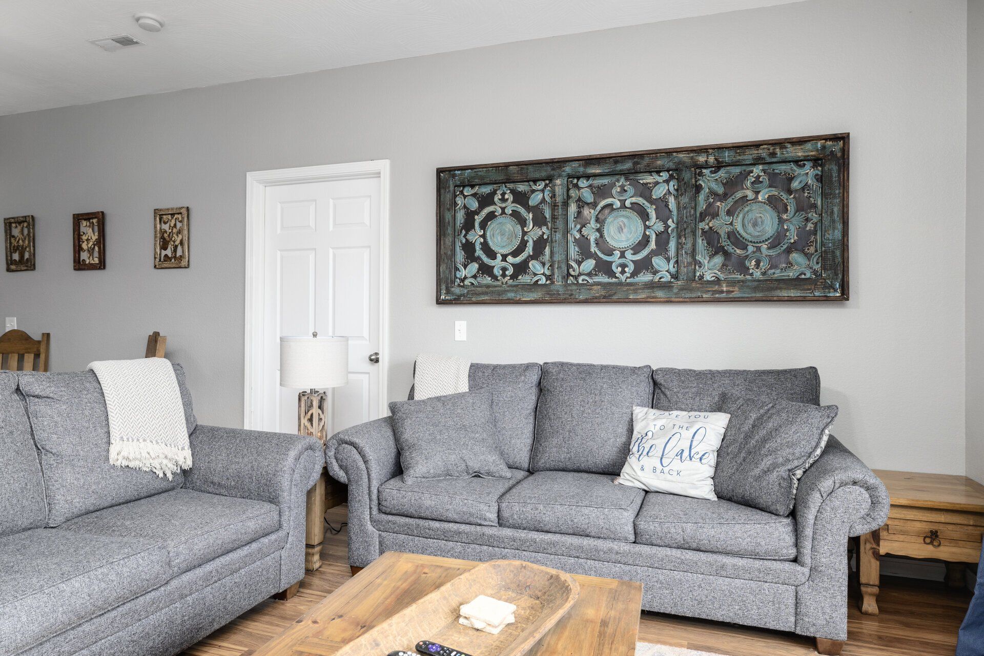 Modern living room with gray sofas, wood coffee table, wall art, and a white door