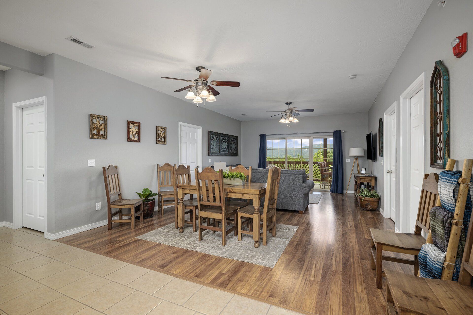 Open-concept dining and living room with wooden table, gray sofa, ceiling fans, and hardwood floors