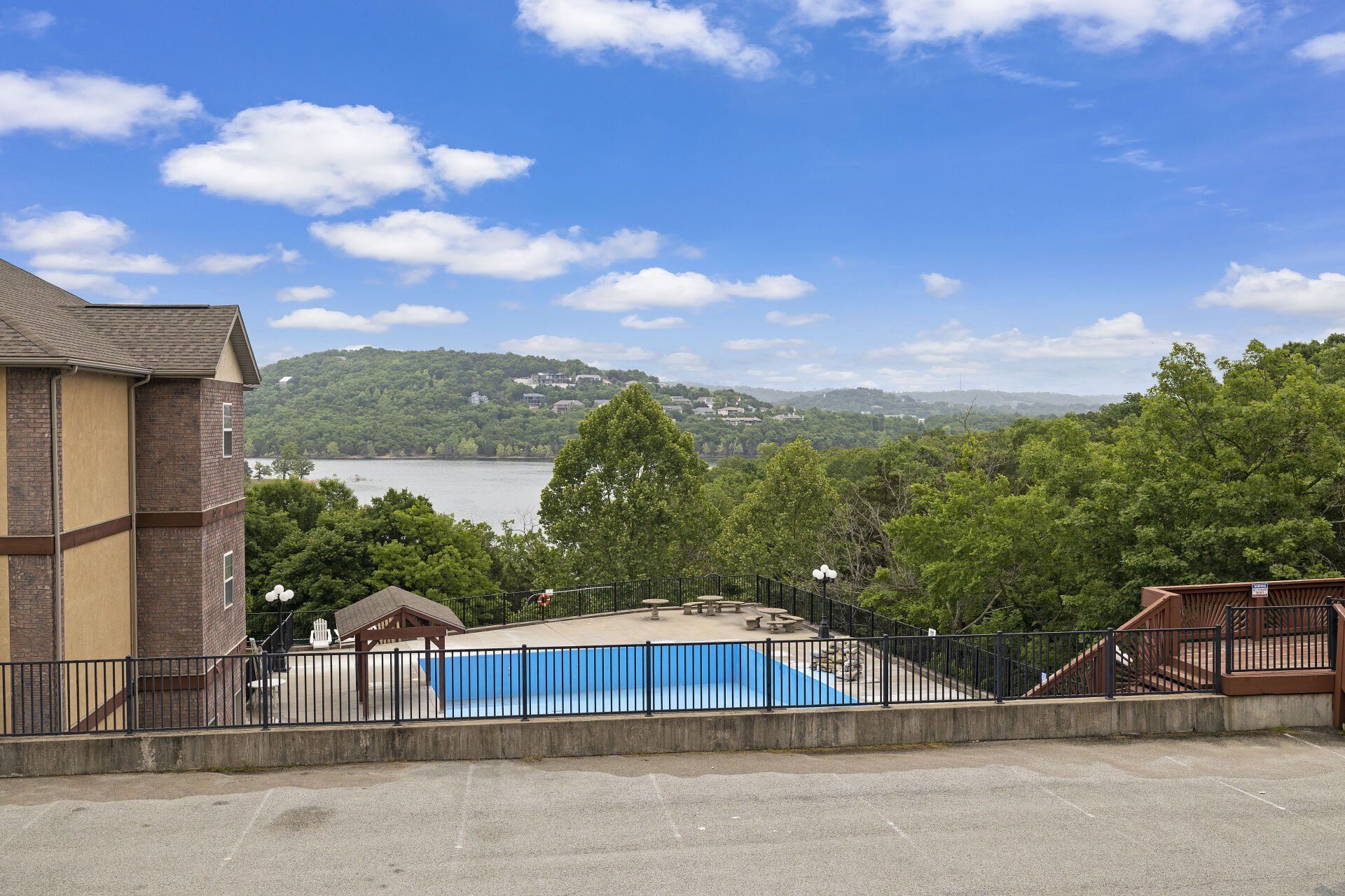 Pool overlooking lake and green hills under a partly cloudy blue sky