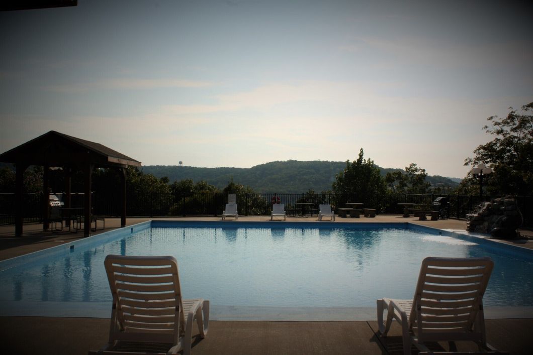Pool with lounge chairs overlooking a calm hillside at sunset