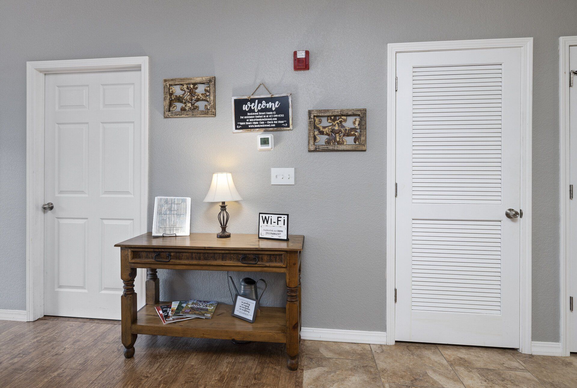 Interior hallway with gray walls, white doors, console table, lamp, and wall decor