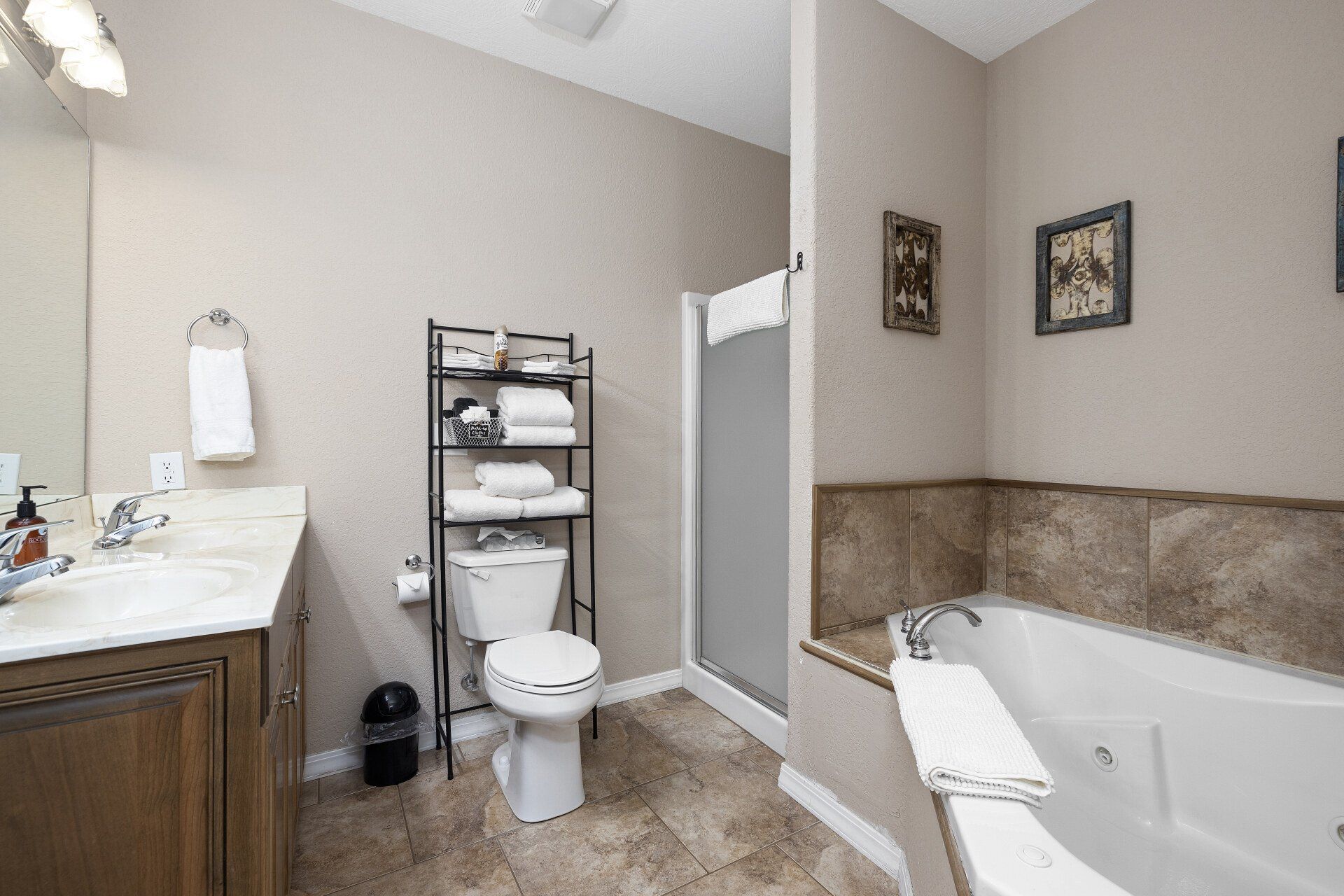 Bathroom with vanity, toilet, shower, and bathtub in beige and brown tones