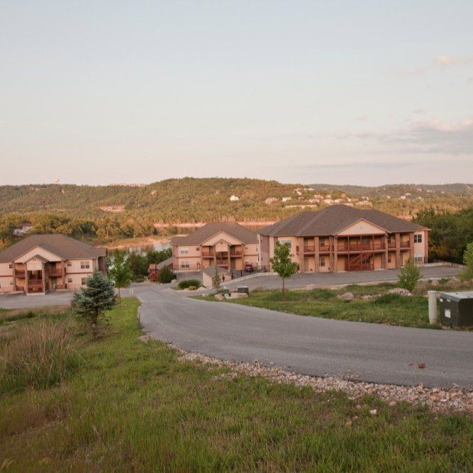 Residential buildings beside a winding road in a hilly landscape at sunset
