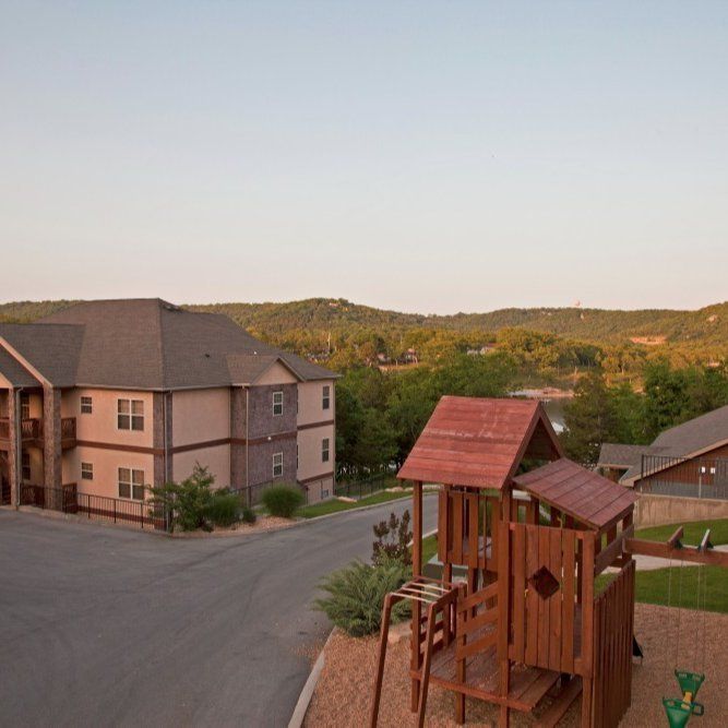 Residential buildings beside a playground at sunset, with hills in the background