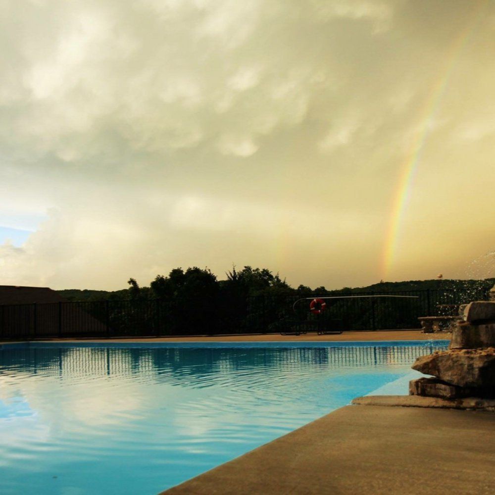Swimming pool at sunset with cloudy sky and a rainbow over the horizon