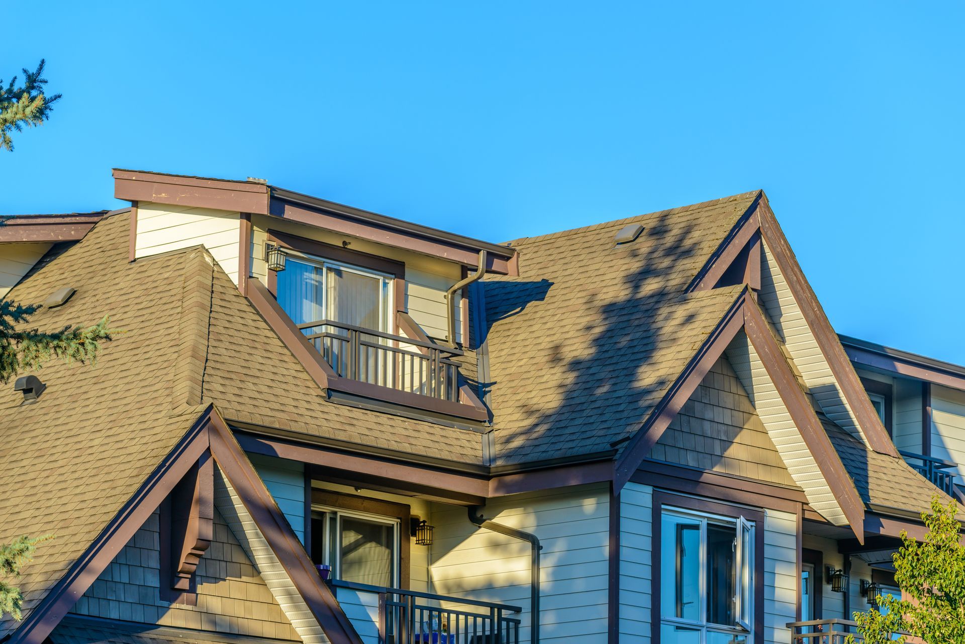 Tan roofed suburban house with dormer windows under a clear blue sky