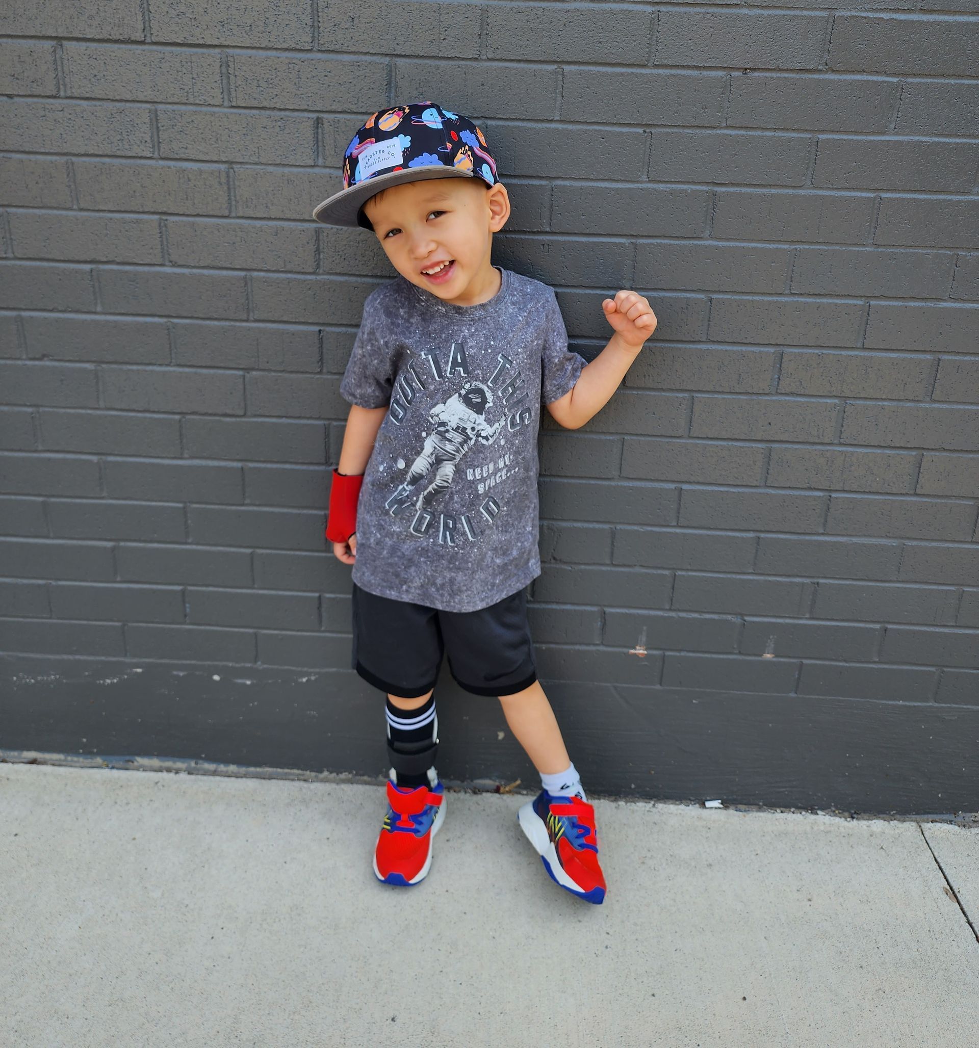 Julian standing outside his school against a brick wall with a smile on his face.