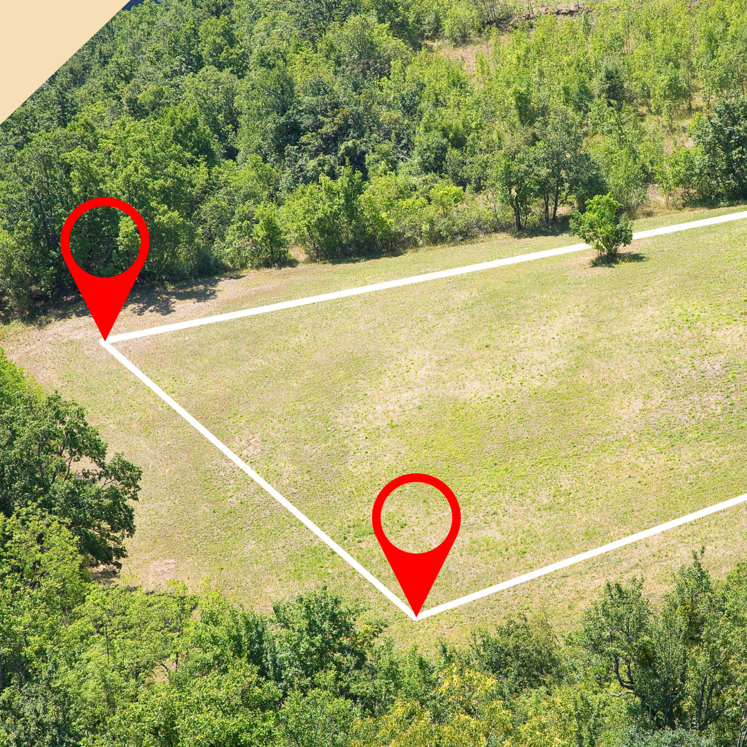 Aerial view of a grassy field with white boundary lines and two red location markers, surrounded by trees.