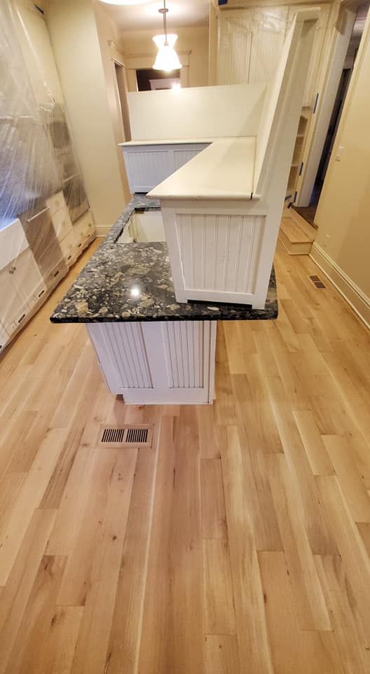 A white kitchen island with a dark granite countertop and a white L-shaped corner bench sitting on top.