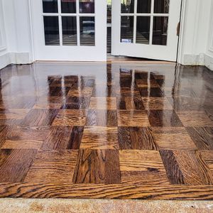 A high-gloss, brown parquet wood floor reflecting a set of white French doors in an indoor space.