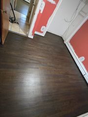A room with dark brown hardwood flooring, white baseboards, and walls partially painted in red.