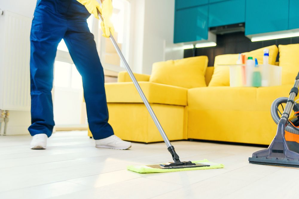 Person Mopping a Light-Colored Floor; Yellow Gloves, Sofa — Port O' Call Cleaning In Cannon Valley, QLD