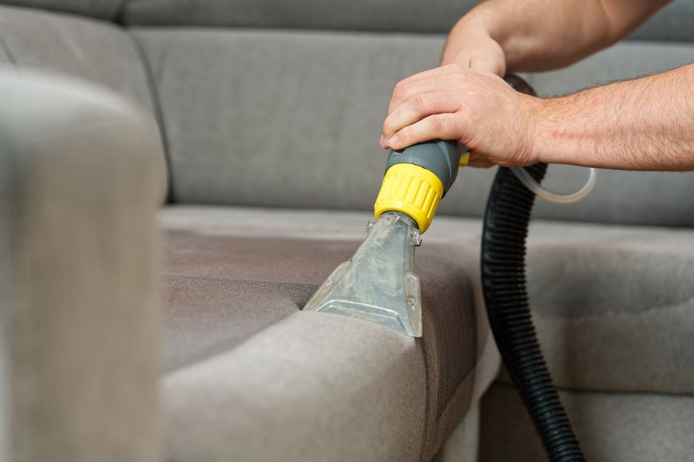 Hand Vacuum Nozzle Cleaning a Gray Sofa Cushion — Port O' Call Cleaning In Cannon Valley, QLD