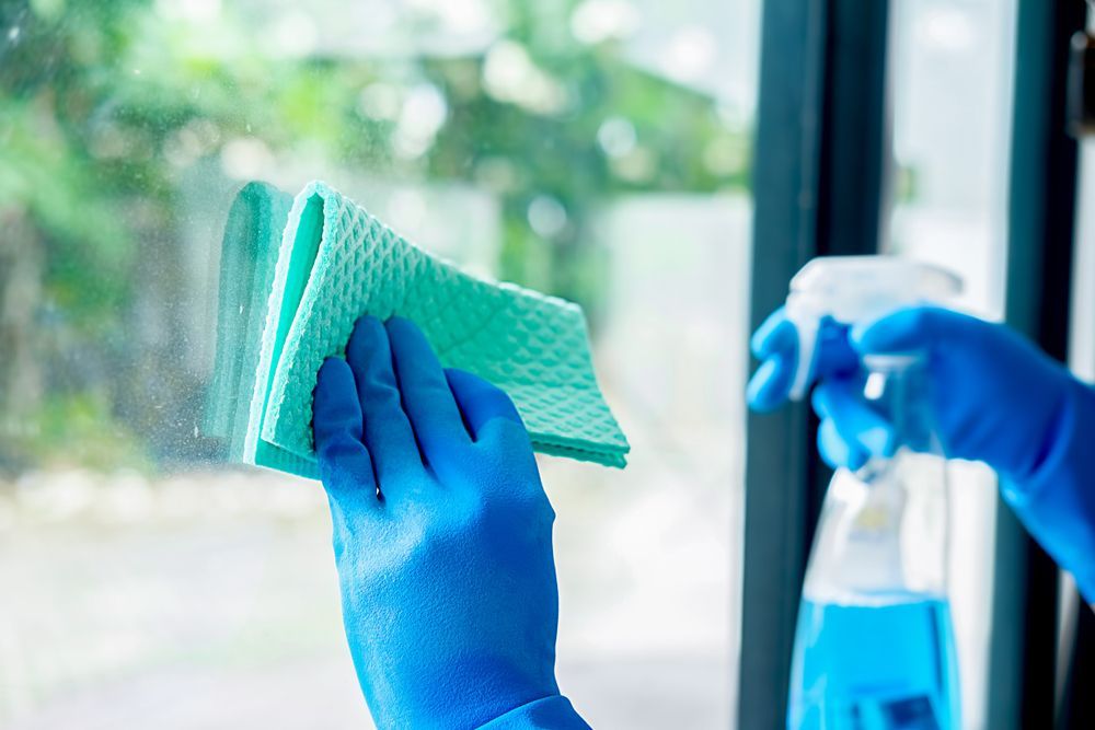 someone with blue gloves, spray and whipping a window — Port O' Call Cleaning In Airlie Beach, QLD