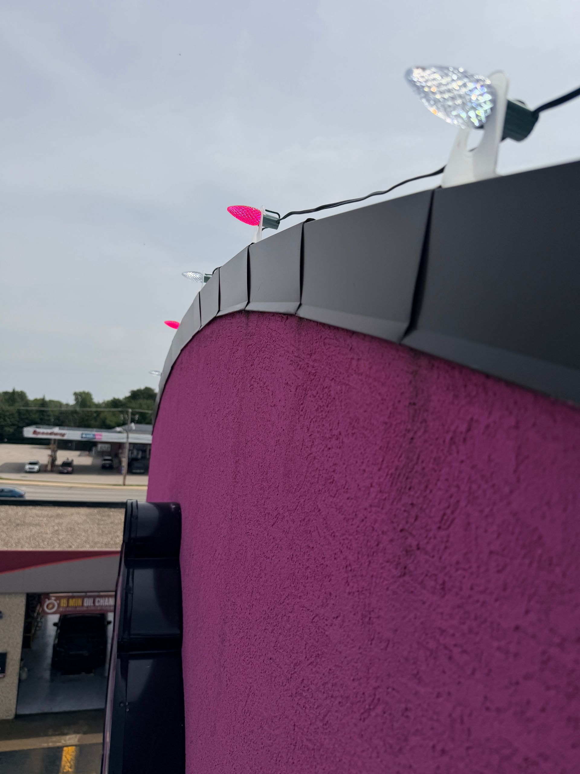 Commercial Christmas light installation on a Bourbonnais IL storefront parapet with pink and cool white C9 LED bulbs