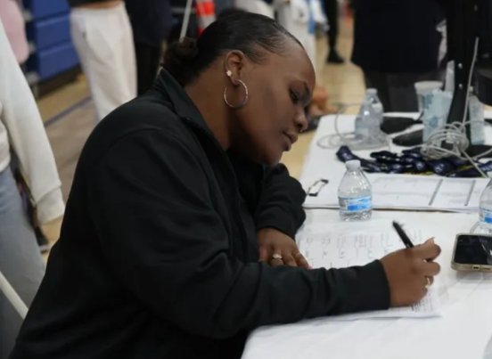 A woman is sitting at a table writing on a piece of paper