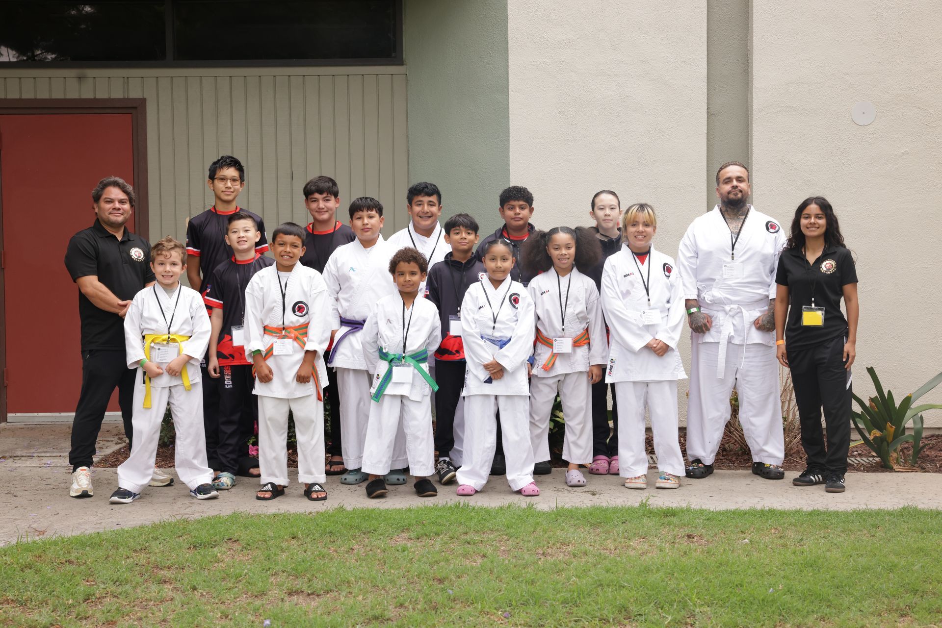 Martial arts group in white gis posing outdoors in front of a building
