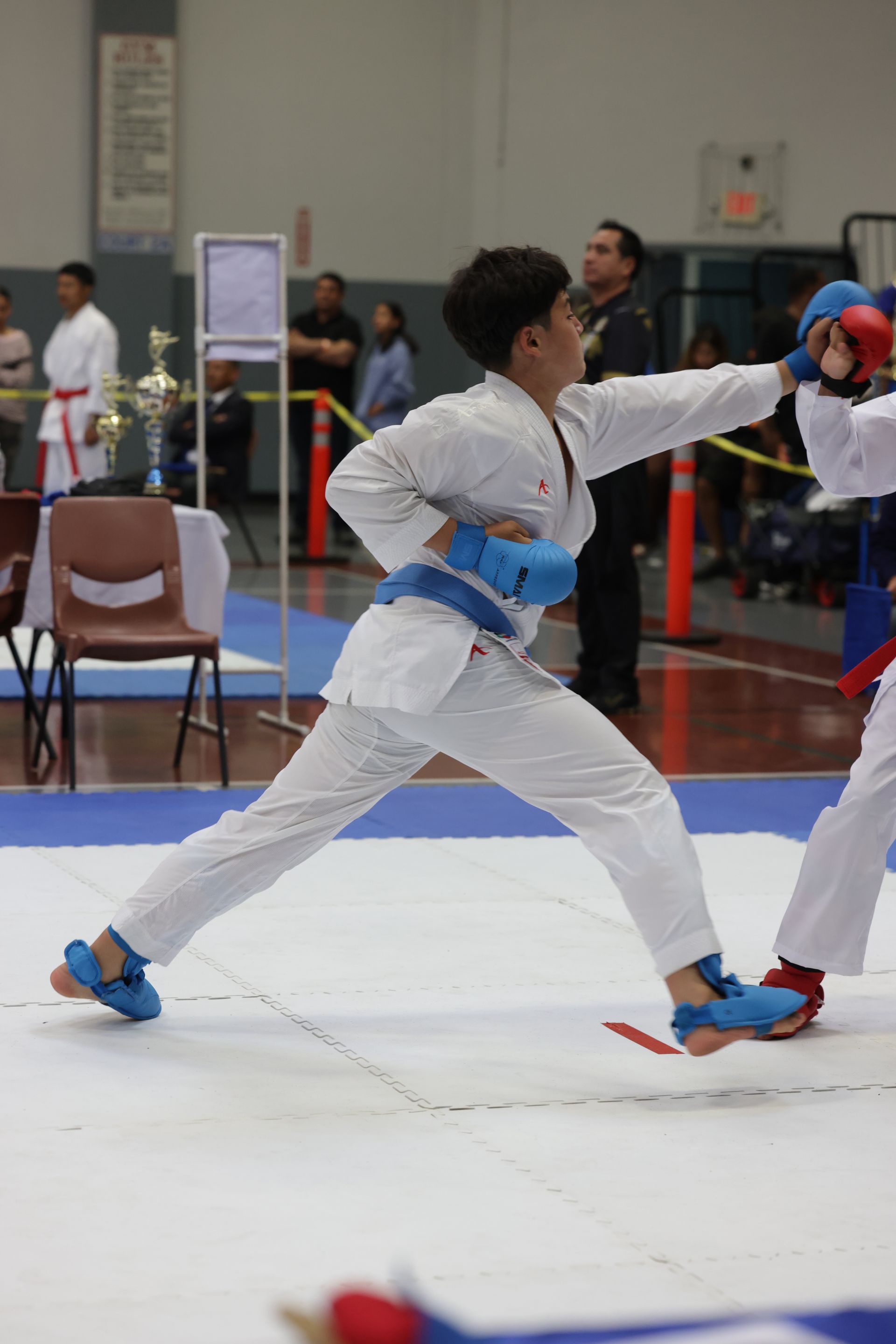 Two fencers in white gear lunge during a bout on a competition strip