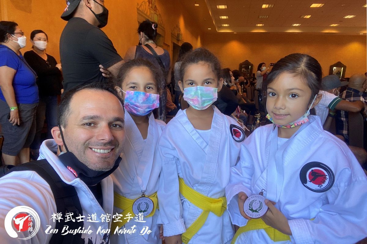 A man and three girls wearing masks are posing for a picture.