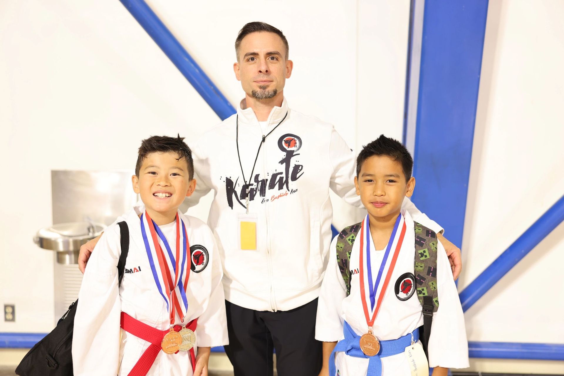 A man is standing next to two young boys wearing medals.