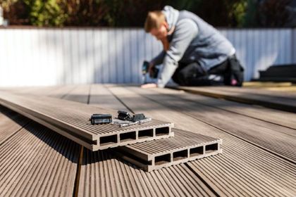 Decking boards being installed on a wooden patio by a blurred worker in the background
