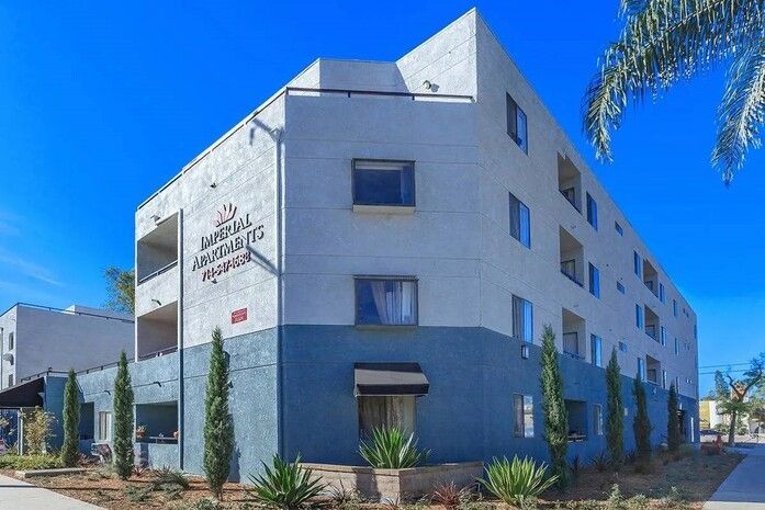 A large apartment building with a palm tree in front of it.