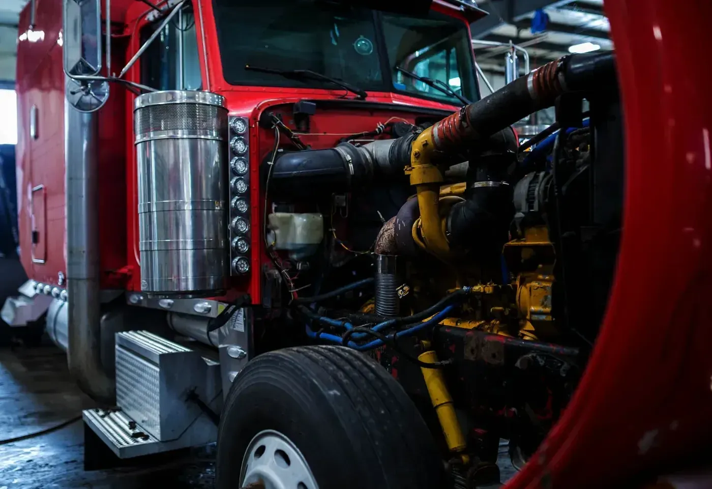 Semi-truck in a service bay with the hood open for diesel engine diagnostics and repair