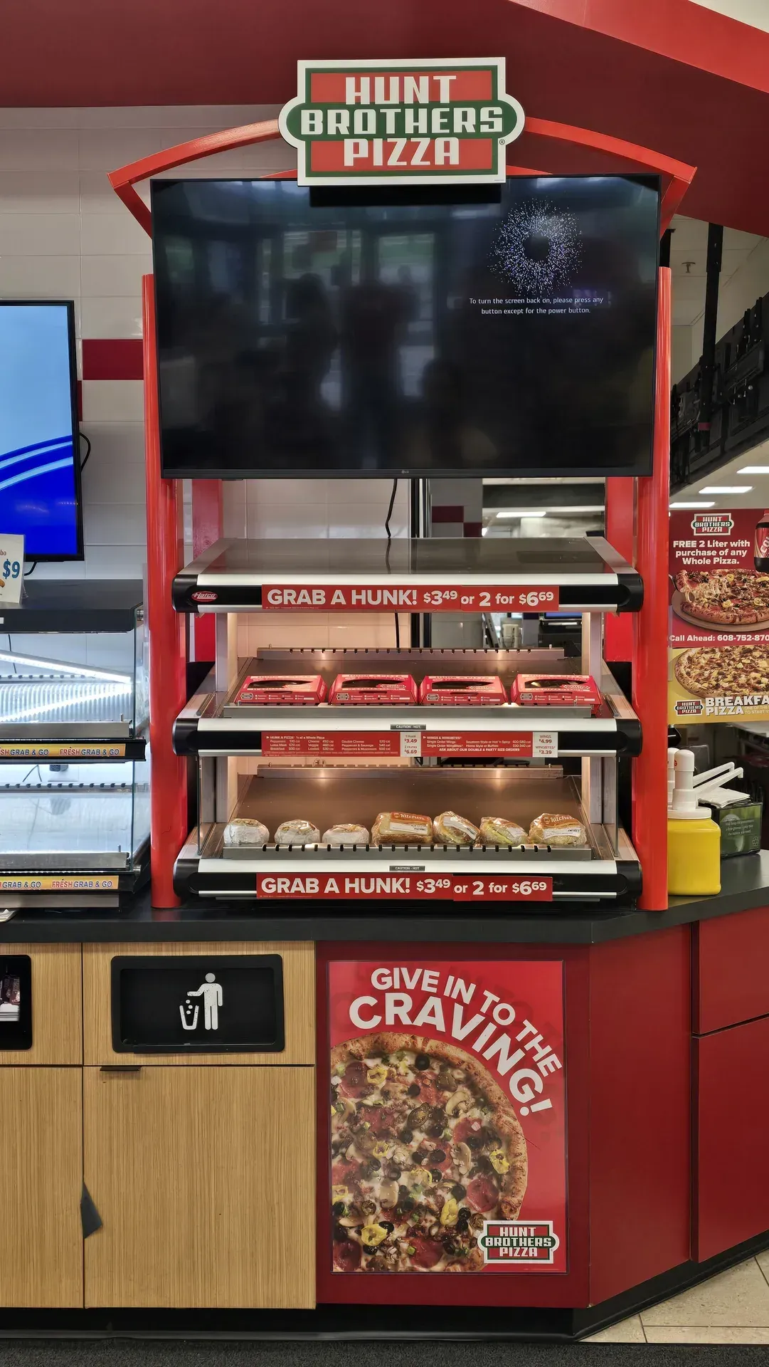 Hunt Brothers pizza kiosk with menu screens and red counter in TA Janesville gas station.