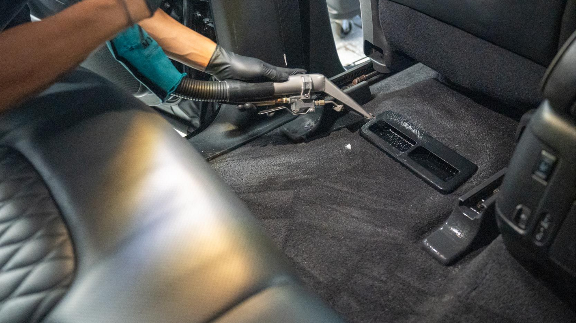 Carpeted car interior with a black seat, exposed wiring, and a center console by the rear floor