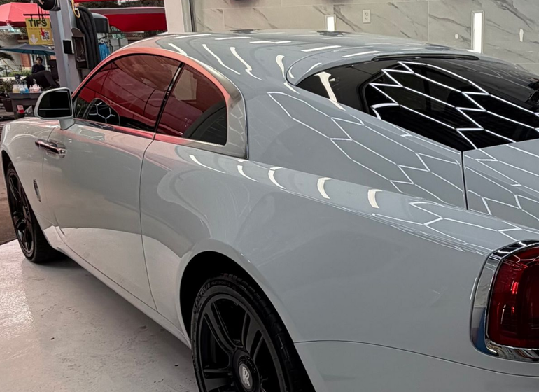 White luxury coupe parked indoors with dark tinted windows and black wheels