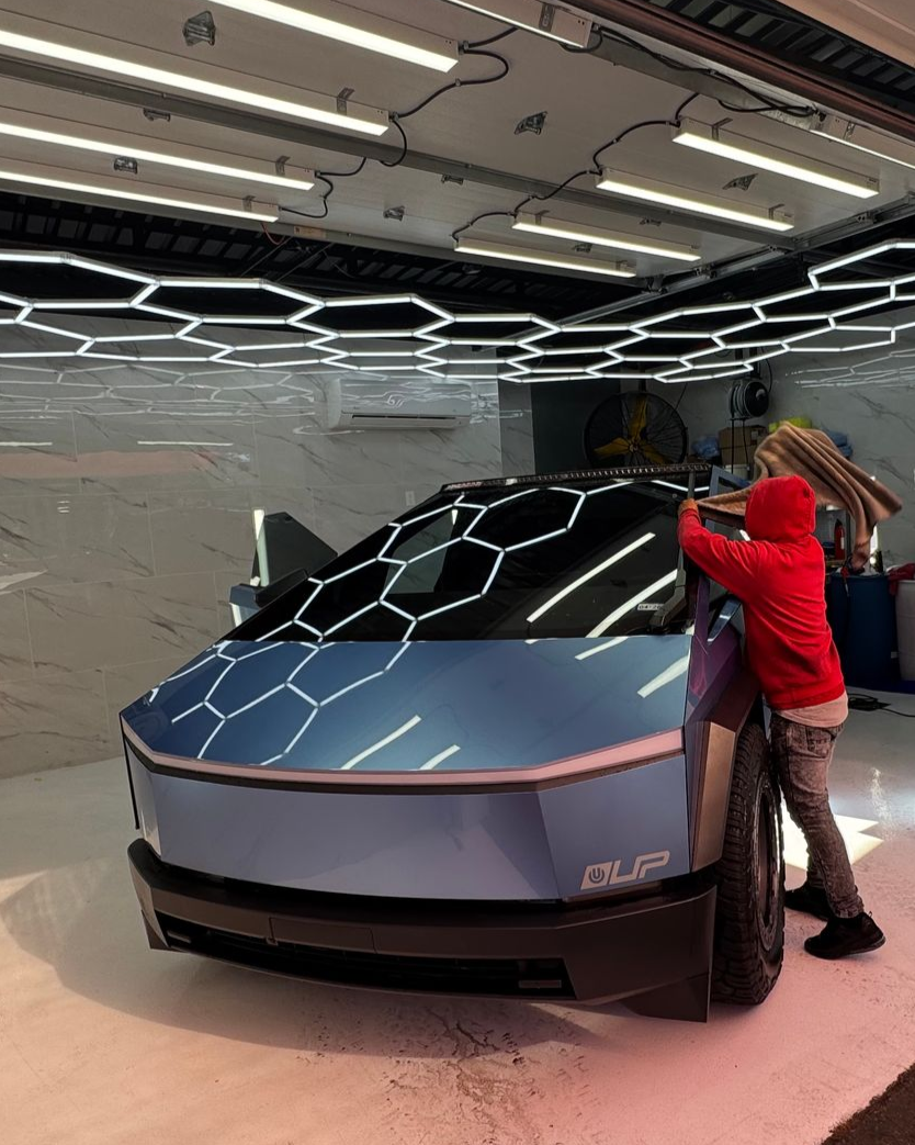 Two people examining a futuristic silver-blue concept truck in a showroom.