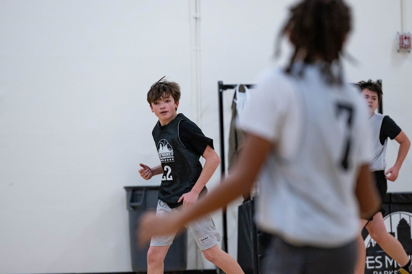 Three youth basketball players move across an indoor court, focusing on play during a practice or game.
