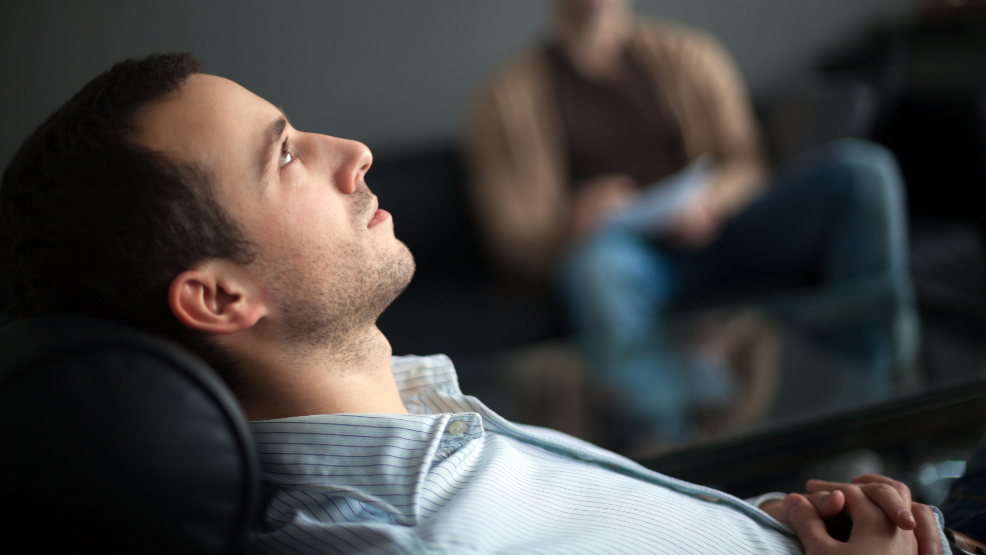 A man is laying in a chair with his eyes closed.