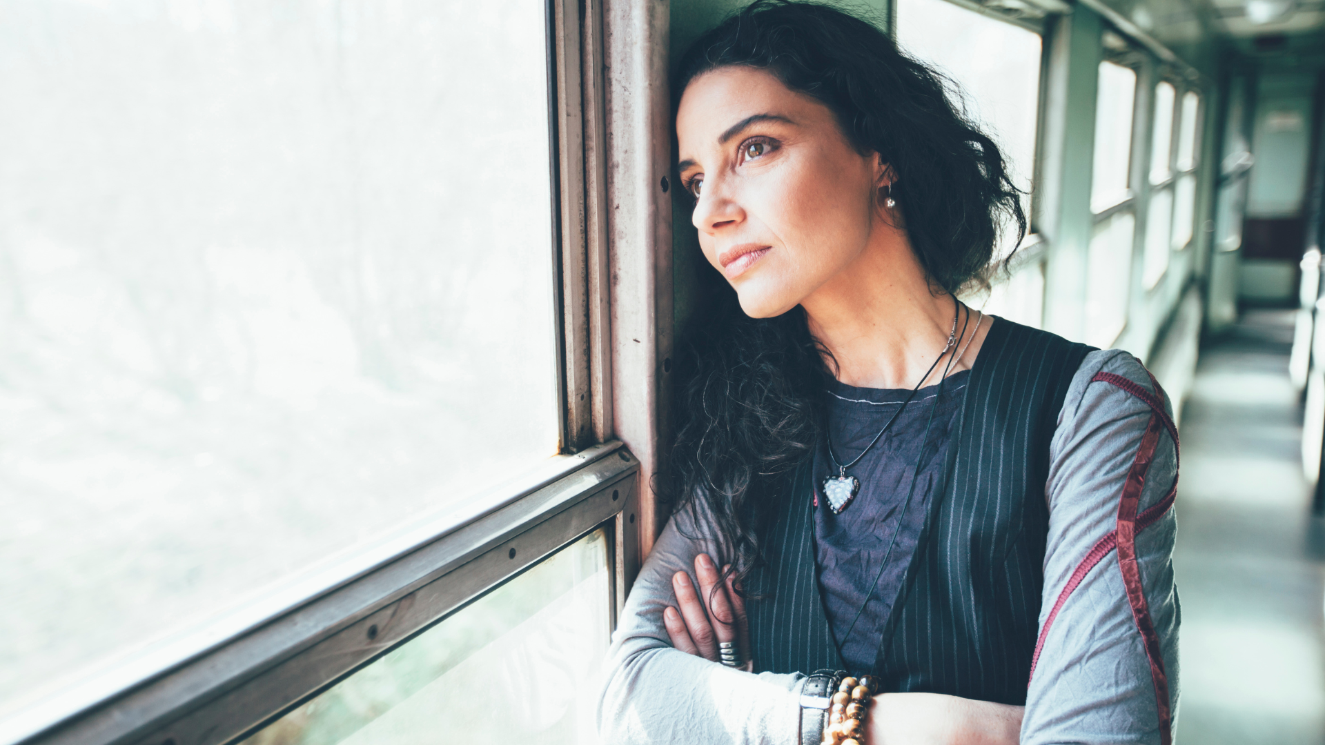 A woman is leaning against a window on a train.